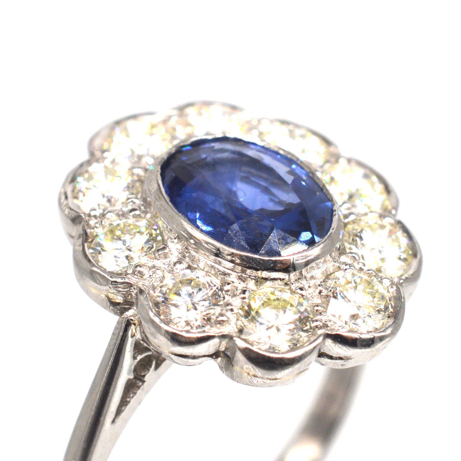 Vintage platinum sapphire and diamond cluster ring featuring a central sapphire surrounded by diamonds.
