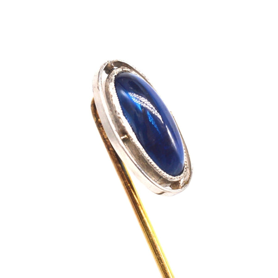Art Deco platinum tie pin featuring a sapphire set in an open circular band, circa 1920s.