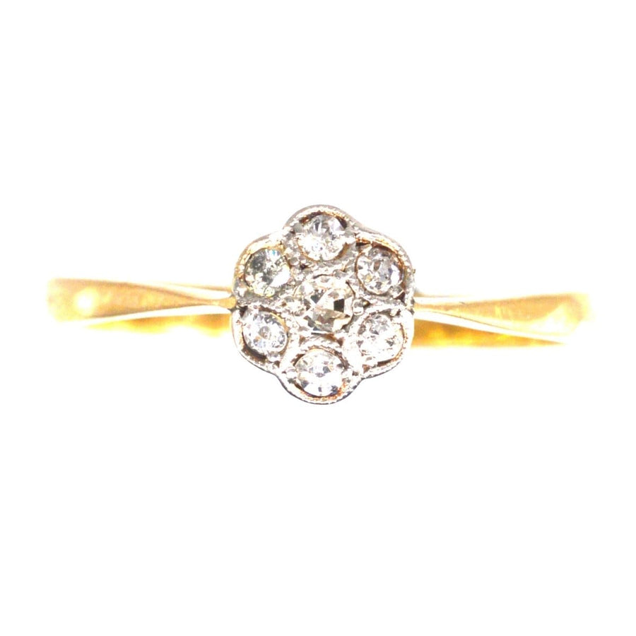 Edwardian diamond daisy cluster ring with millegrain setting on a gold band, perfect for engagement.