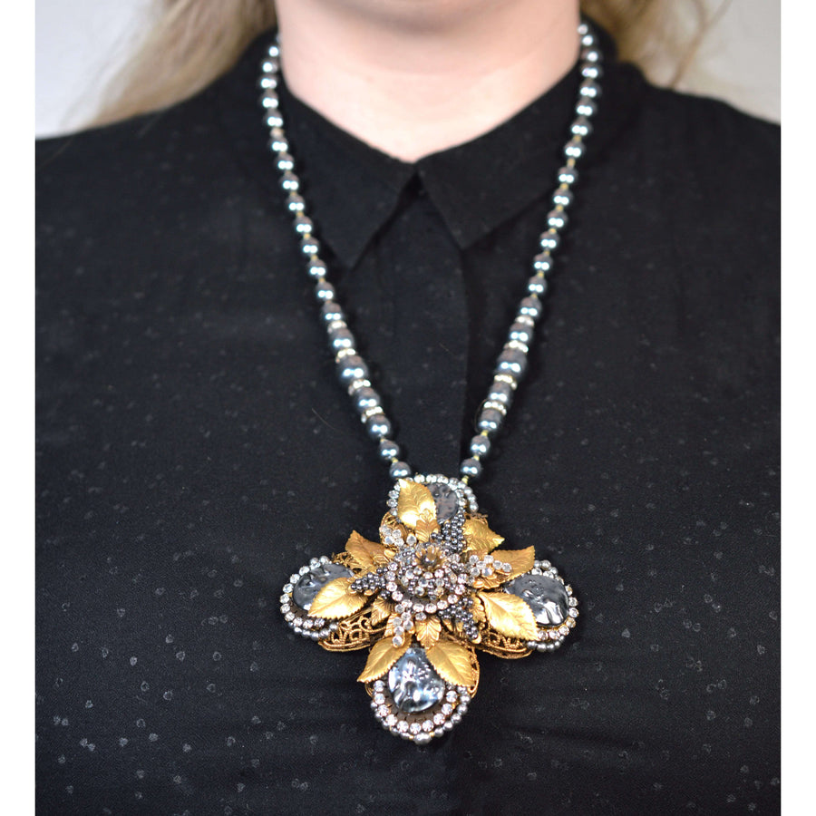 Mid Century Miriam Haskell gold gilt necklace with black pearls and rhinestone cross pendant worn by a model.