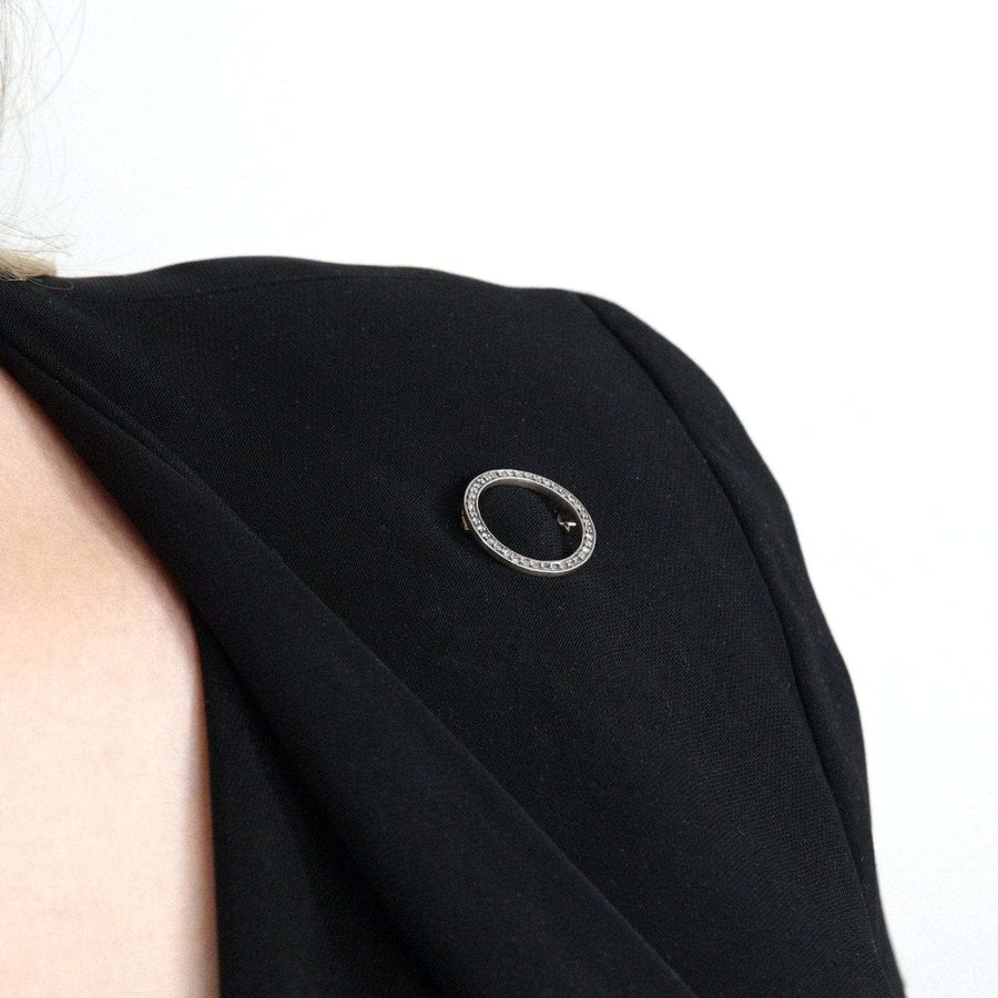 Art Deco 15ct gold and platinum diamond circle brooch worn on a black dress, showcasing its elegant design.