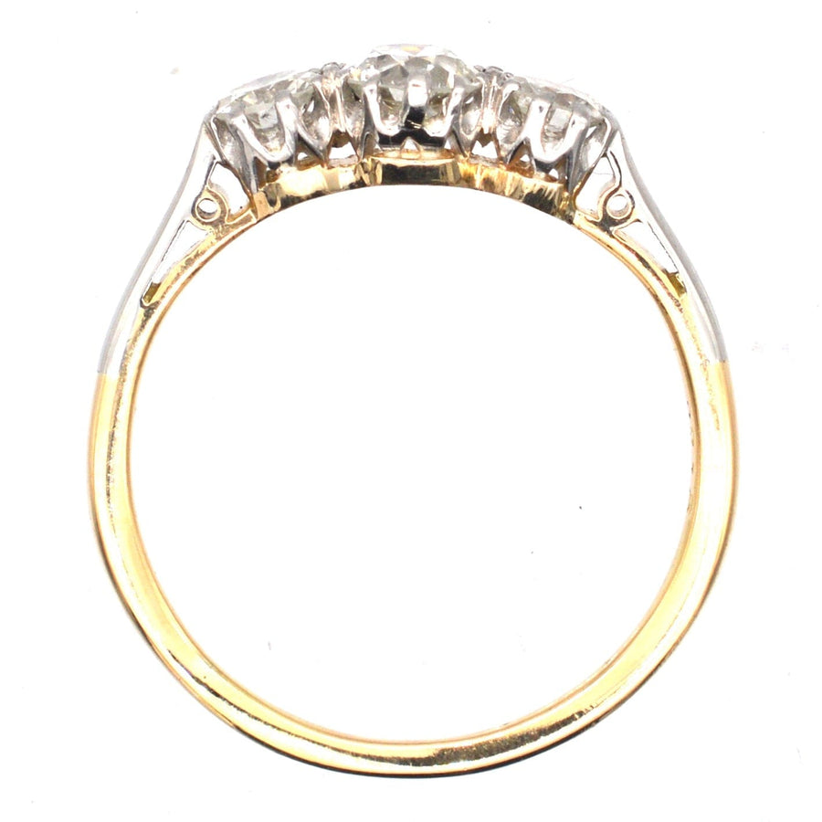 Art Deco platinum and 18ct gold diamond three stone ring, showcasing clear, white diamonds in a low-profile setting.