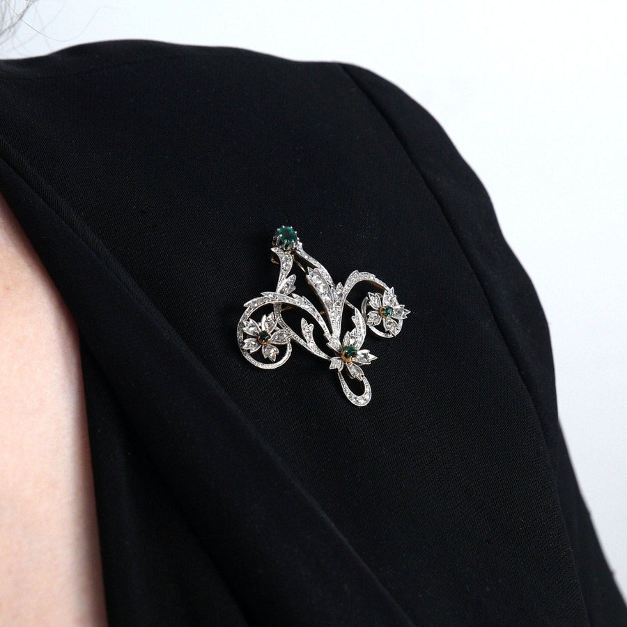 Edwardian 15ct gold and platinum brooch with emerald and rose diamonds worn on a black garment.