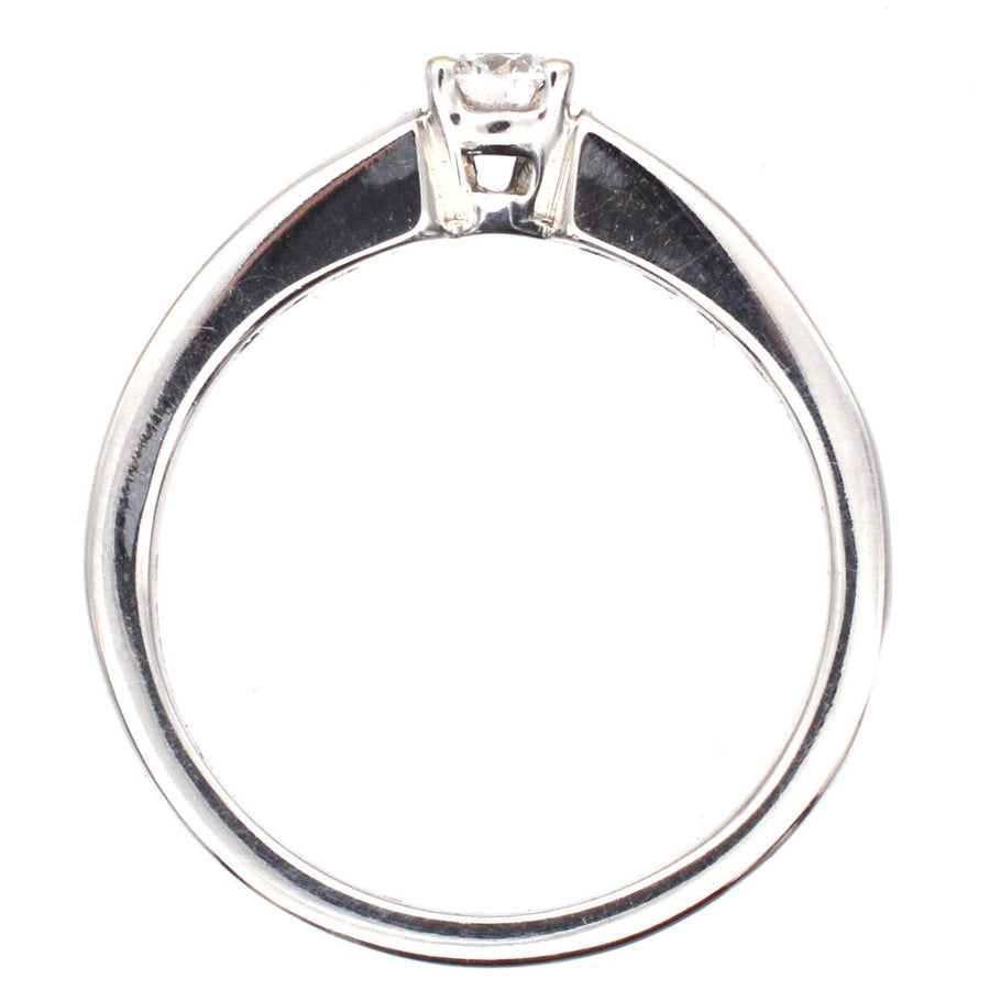 Modern 18ct white gold solitaire ring featuring a brilliant cut diamond in center and channel-set diamond shoulders.